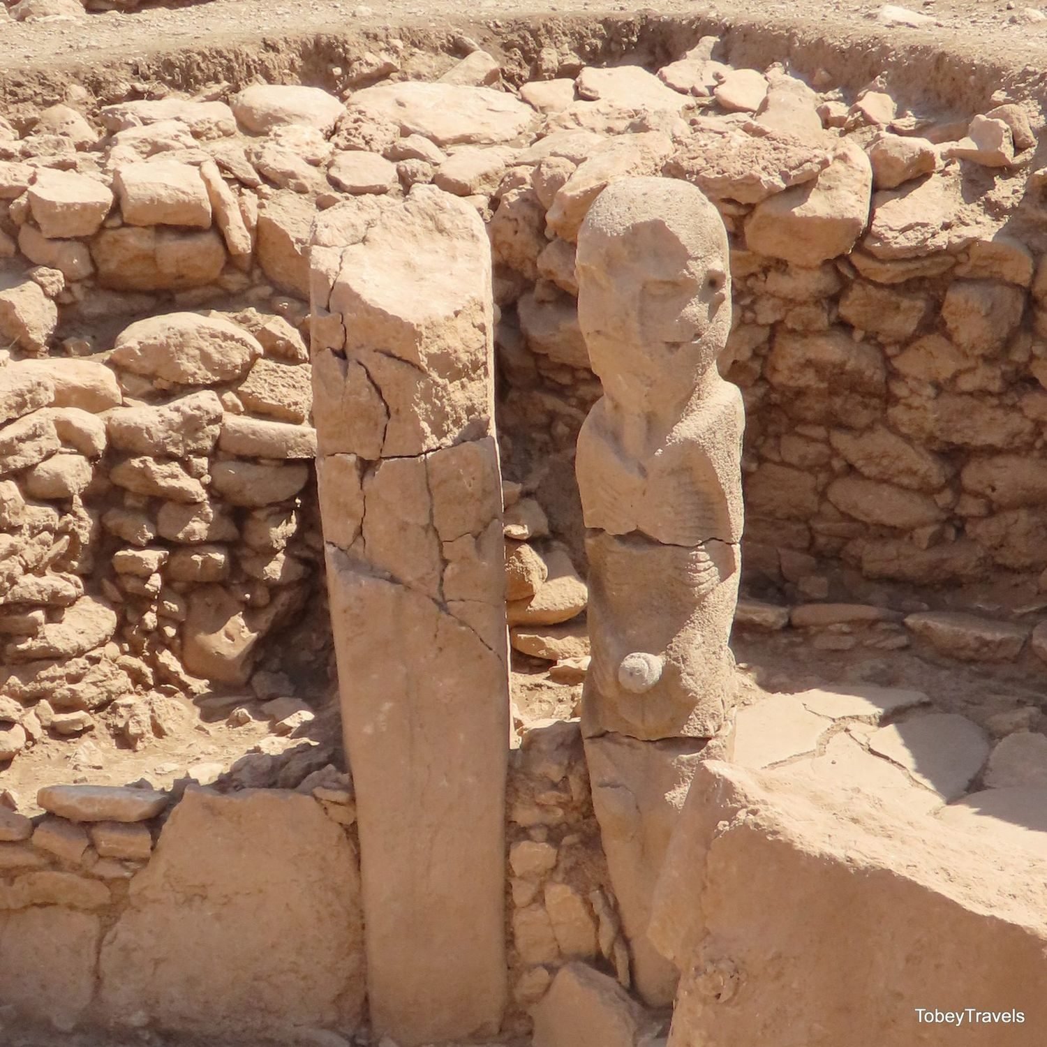 A porthole stone at Karahan Tepe, standing beside a phallus-shaped statue in Area 08 — the same perforated-slab idea, 40 km from Göbekli Tepe.