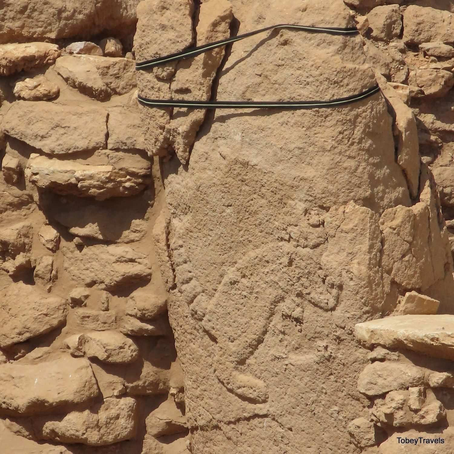 A four-legged animal carved in low relief running down the shaft of a pillar in a wall