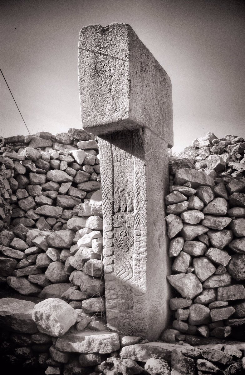Side of a central T-pillar of Enclosure D with a carved arm, hand, belt and hanging fox-pelt loincloth