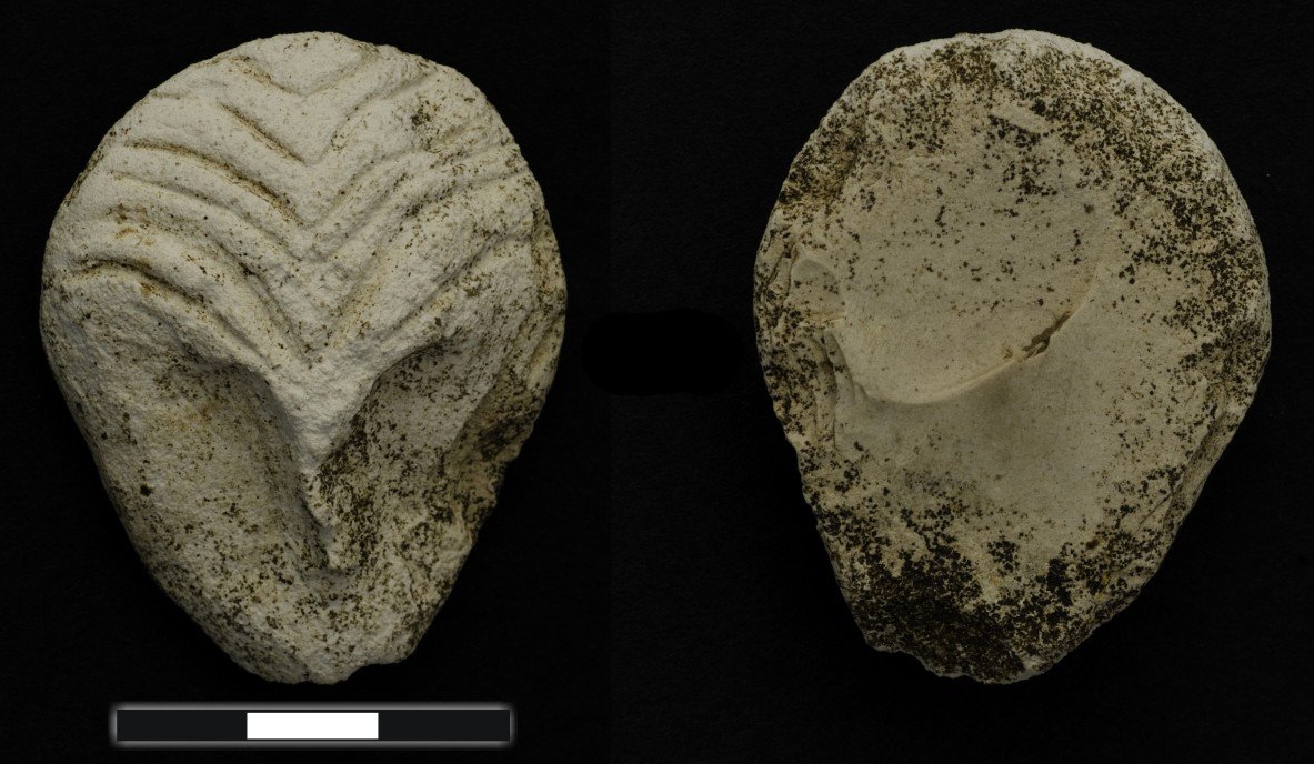 A miniature stone mask (4.7 cm) from Göbekli Tepe, its brow engraved with curved chevrons that may show a headdress. The site has produced several such miniature masks and one larger-than-life example — durable copies, most likely, of real masks once worn in performance.