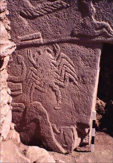 Pillar 43, the 'Vulture Stone'. Low and to the right, a small human figure is shown without its head, near a bird — the clearest carved statement of the site's death-and-the-head symbolism.