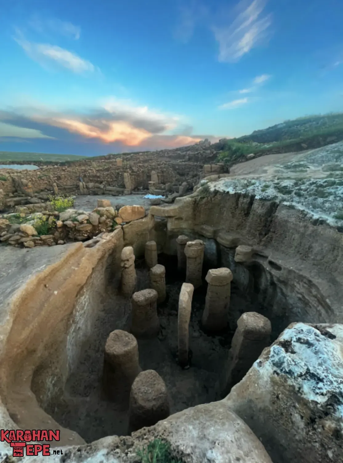 Sunken rock-cut pit filled with rounded stone pillars, seen from above at dusk