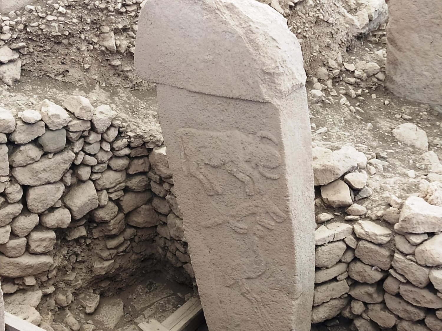 A T-pillar set against the walling of its enclosure. Read this way, standing inside would have felt less like an open ring and more like entering a dim, covered room.