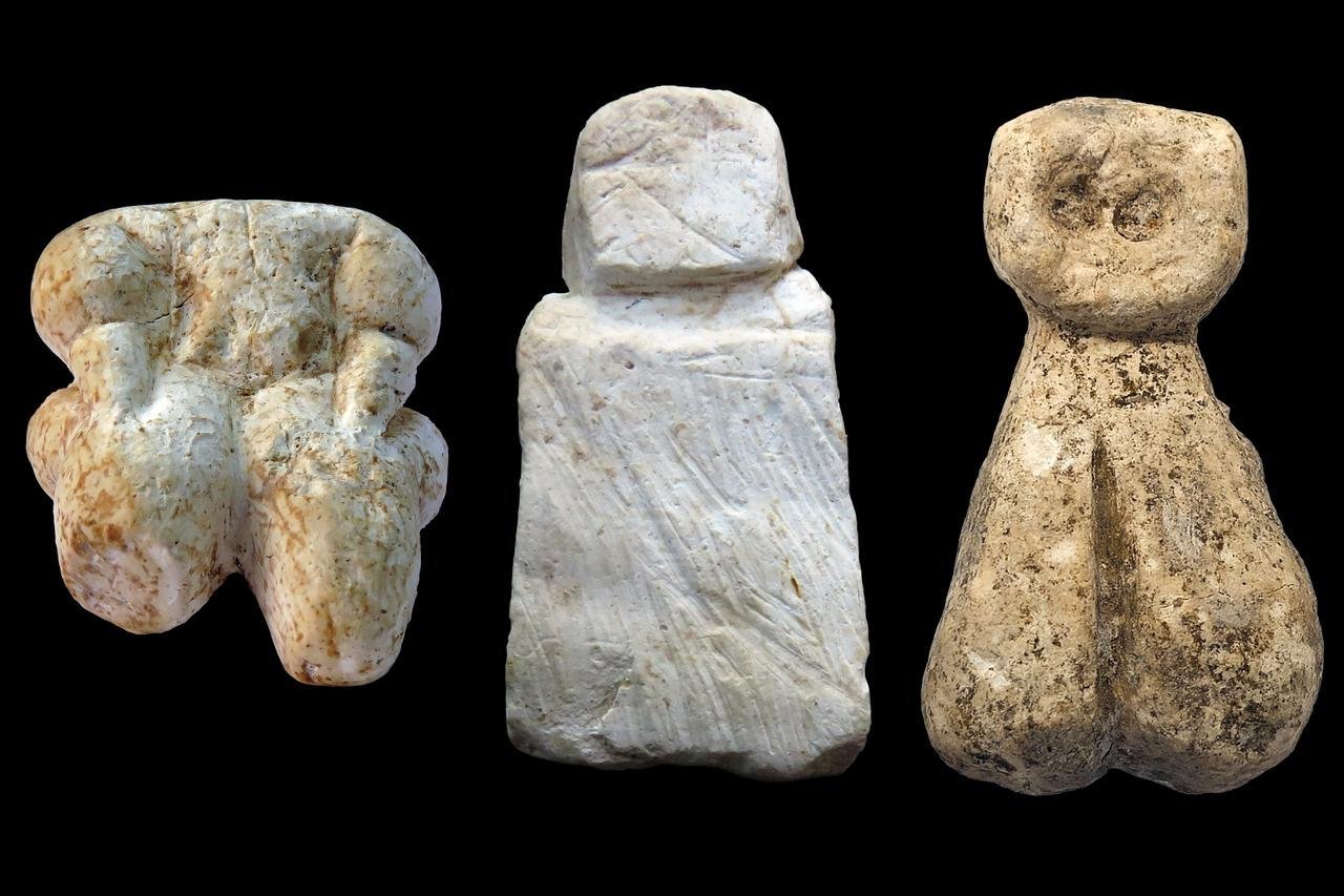 Three small limestone human figurines from Gürcütepe against a black background
