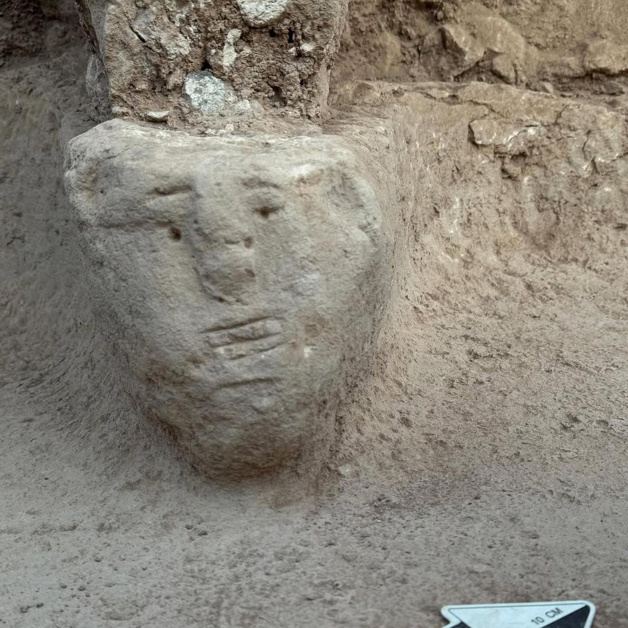 A human face carved in relief on the stone base at the foot of a standing pillar at Sayburç