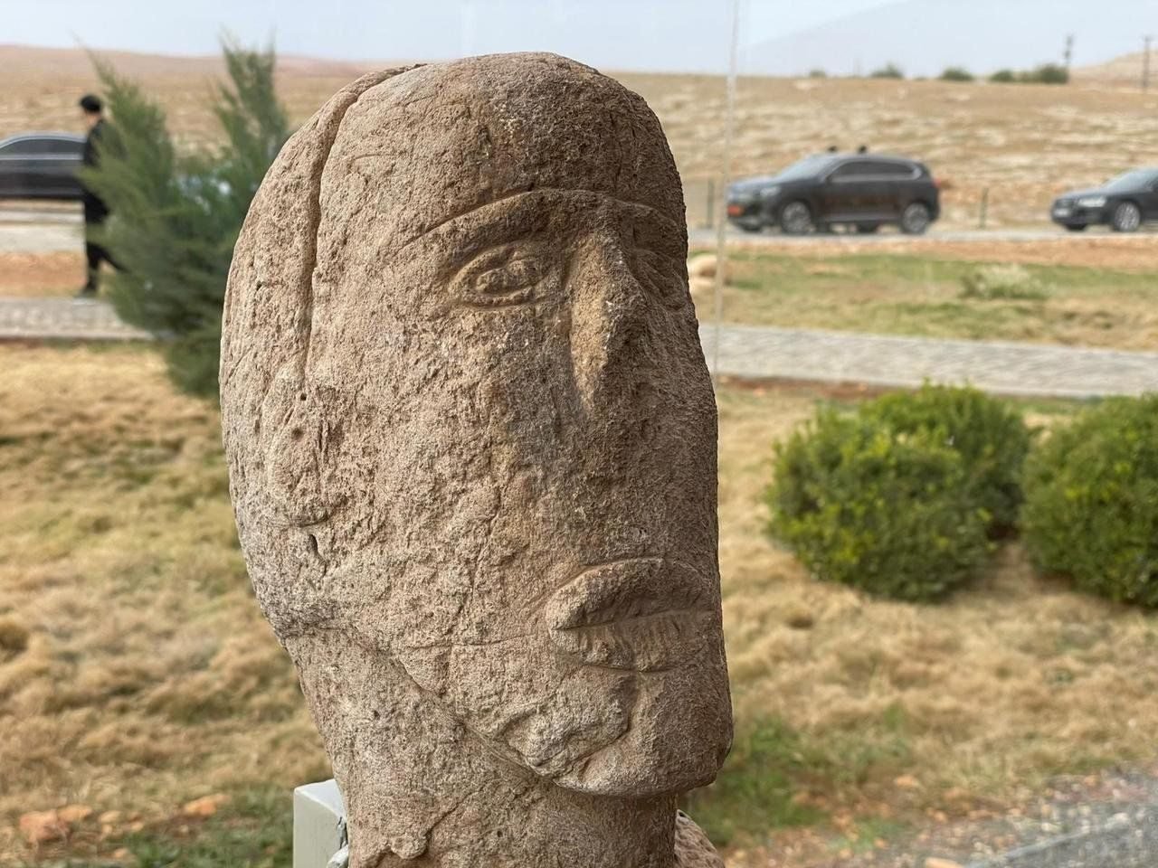 Close view of the statue's face — the eyes, nose and the mouth rendered with cross-hatched lines that read as stitching, the detail that gives the figure its name.